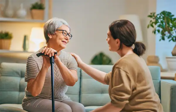 Patients et soignants connectés : jeune femme soignante à domicile avec femme âgée souriante